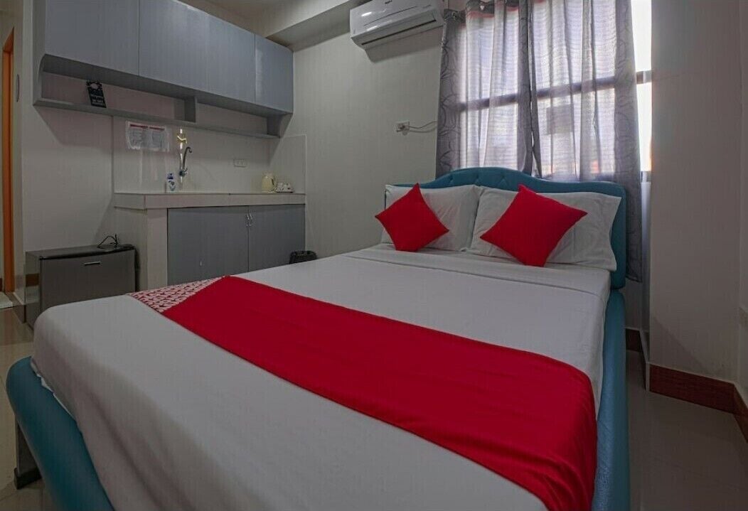 Una habitación de hotel con una cama, un escritorio pequeño, un espejo y una ventana con cortinas.