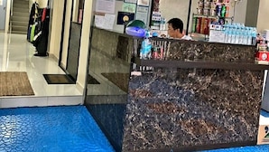Zona de recepción de un hotel con un mostrador de mármol, un reloj y una cámara de seguridad.