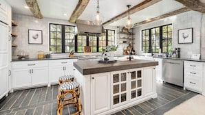 A spacious kitchen with a large island, white cabinetry, and exposed wooden beams.