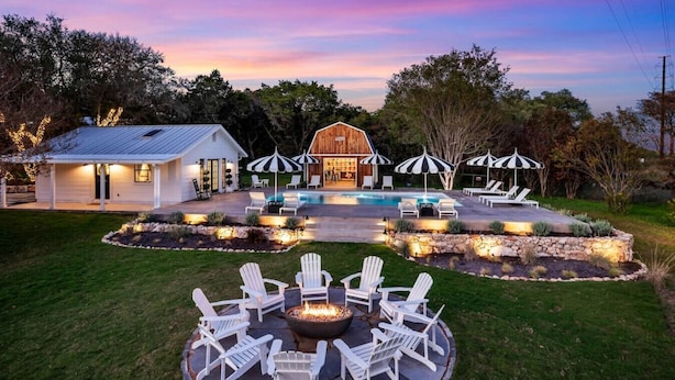 A modern house with a swimming pool, outdoor seating, and a fire pit.