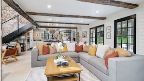 A modern living room with a gray sectional sofa, wooden coffee table, and a staircase leading to an upper level.