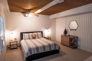 A bedroom with a bed, bedside tables, a dresser, a mirror, and a ceiling fan. - The Ope! North Hideaway (Bellaire)