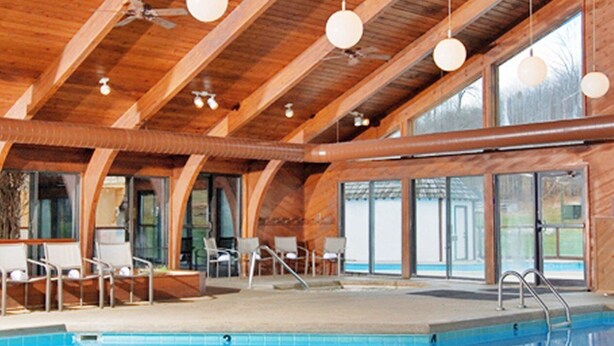 An indoor swimming pool with wooden beams, large windows, and lounge chairs. - The Ope! North Hideaway (Bellaire)