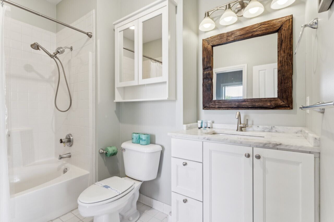 Une salle de bain comprenant une baignoire, des toilettes, un meuble-lavabo avec un miroir et une douche.