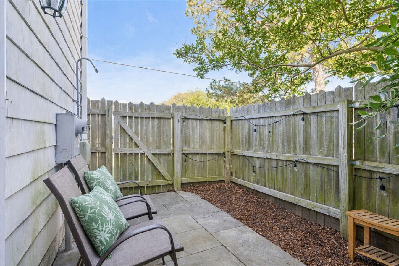 Un espace patio agrémenté d’une clôture en bois, d’un banc et d’une petite table.