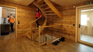 A wooden interior with a spiral staircase, a kitchen area, and a door leading outside. - Luxury chalet/seminar vacation home with sauna, in the mountains of the Bregenzerwald (Bezau)