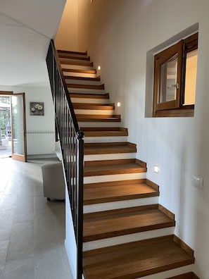 Stairs lead to an upper floor in a well-lit room with a window.