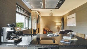 A modern kitchen with a built-in espresso machine, a stovetop, and a digital oven display. - Scar View - Getaway for Two | Ridgestone (Kendal)