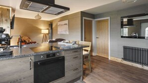 A modern kitchen with a central island, built-in oven, and a large window. - Scar View - Getaway for Two | Ridgestone (Kendal)