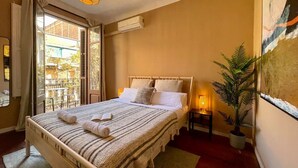 Un dormitorio con cama, mesita de noche, lámpara y una planta en maceta.