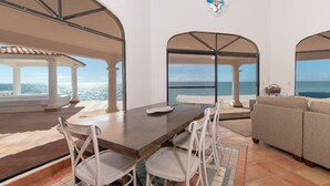 A spacious outdoor area with a dining table and chairs, a sofa, and a view of the sea.