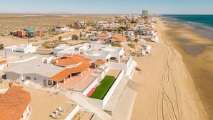 An aerial view of a coastal town with buildings, a beach, and a clear sky.