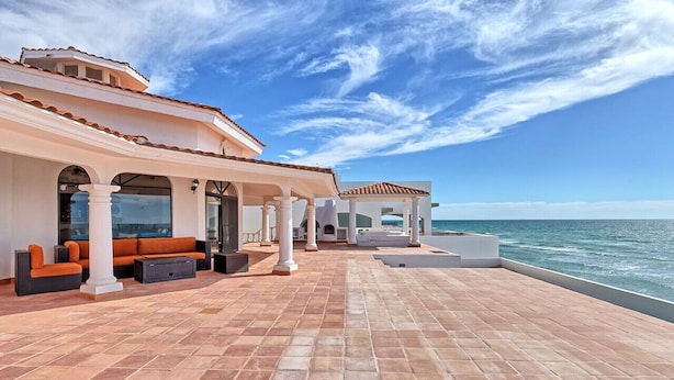A covered outdoor area with a patio, seating, and a view of the sea.