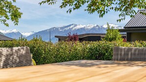 A table and chairs in a garden with a view of snow-capped mountains. - Serenity on Ruby Ridge (Wānaka)