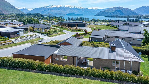 A residential area with modern houses, a driveway, and a mountain backdrop. - Serenity on Ruby Ridge (Wānaka)