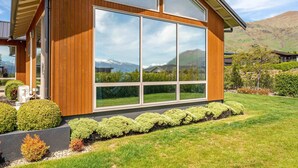 A modern wooden house with large windows and a well-maintained lawn. - Serenity on Ruby Ridge (Wānaka)