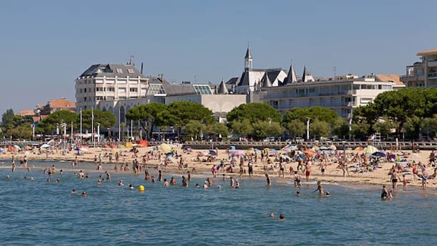 A beach with people swimming and sunbathing, a church with a tall spire, and buildings with a mix of modern and traditional architecture. - Beautiful furnished and comfortable apartment in the center of Bordeaux (Bordeaux)