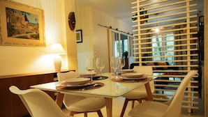 A dining area with a glass table, white chairs, and a wooden cabinet. - Beautiful furnished and comfortable apartment in the center of Bordeaux (Bordeaux)