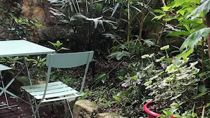 A garden with a table and chairs, surrounded by various plants and a stone wall. - Beautiful furnished and comfortable apartment in the center of Bordeaux (Bordeaux)