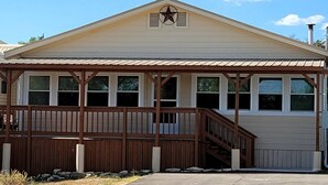 A building with a star emblem on the facade, a wooden porch with a staircase, and a metal roof. - Classic Charm Close To Lake (Canyon Lake)