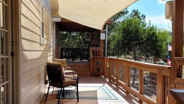 A wooden deck with a covered area, a chair, and a table. - Classic Charm Close To Lake (Canyon Lake)