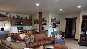 A living room with a brown leather sofa, a coffee table, and a dining area with wooden cabinets and a microwave. - Cleveland Place (Meeker)