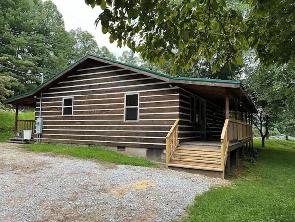 Situated in a wooded setting, this cabin features a porch with stairs leading up to it.
