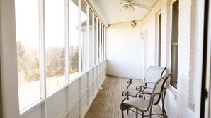 A covered porch with two wicker chairs, large windows, and a ceiling fan. - Holland Estate (Williamstown)