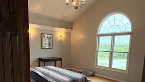 A bedroom with a bed, a chandelier, a window, and a painting on the wall. - Holland Estate (Williamstown)