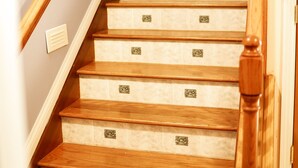 A wooden staircase with a handrail and a light switch on the wall. - Holland Estate (Williamstown)