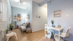 A modern living room with a sofa, a dining table with chairs, a small white table, and a potted plant. - City Nest Apartment by Cloudkeys (Athens)