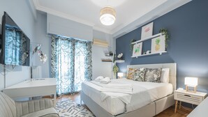 A bedroom with a bed, bedside tables, a desk, and a chair. - City Nest Apartment by Cloudkeys (Athens)