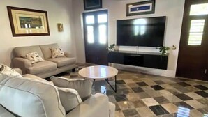 Una sala de estar con sofá, una mesa de centro y un televisor de pantalla plana montado en la pared.
