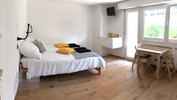A bedroom with a bed, a desk, and a window.