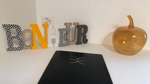 A black folder with 'PHOENIX' logo on a white surface, surrounded by decorative letters and a pumpkin.