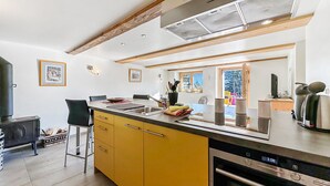 A modern kitchen with a large island, a built-in oven, and a dining area with chairs. - My Cosy Flat in the Mountains (Anzère)
