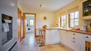 A kitchen with white cabinets, a stainless steel refrigerator, and a tiled floor. - Country farmhouse sleeps 9 with enclosed garden and games barn. (Blairgowrie, Perthshire)
