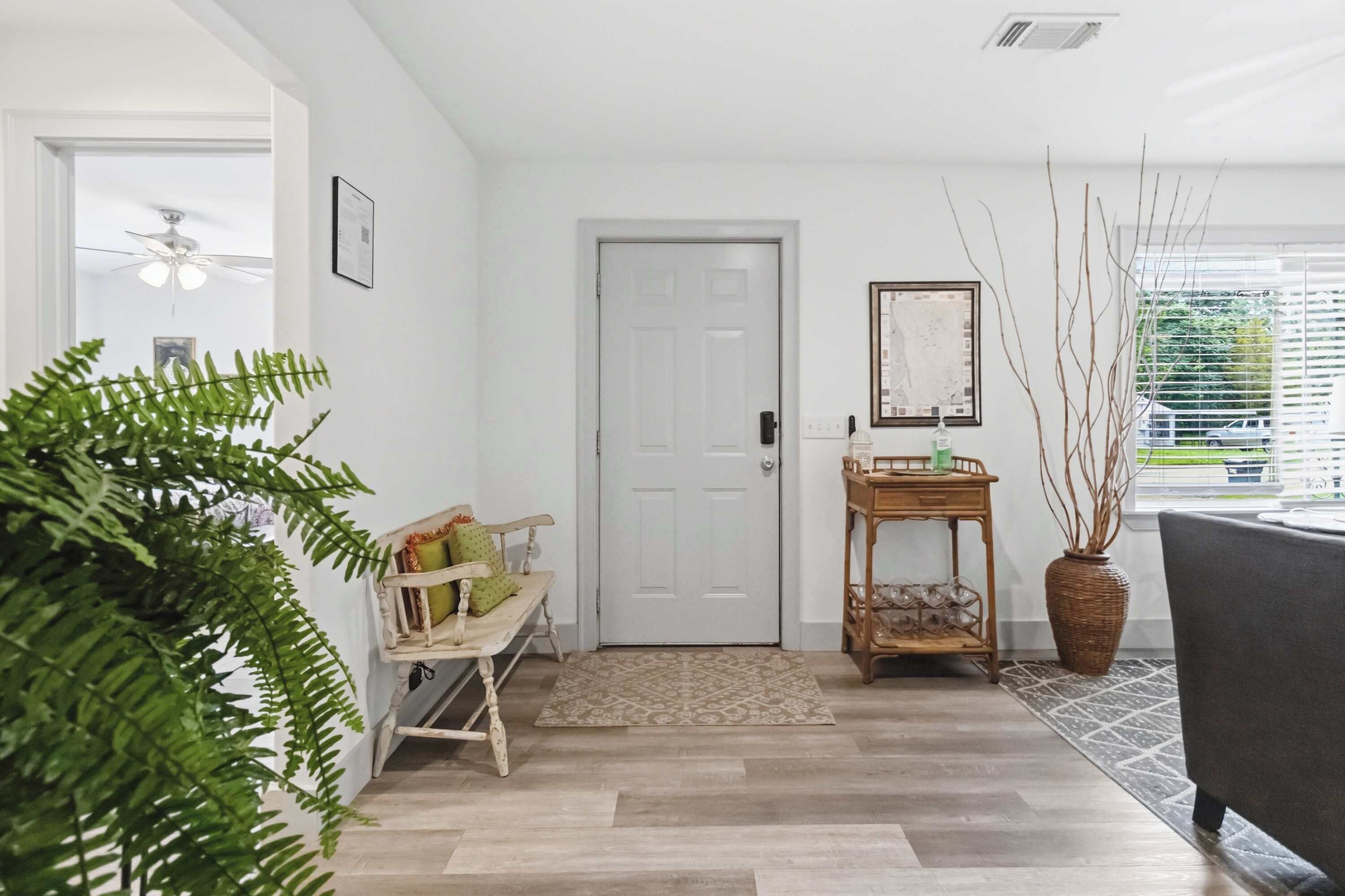 Un intérieur moderne avec un banc en bois, une porte, une petite table avec un vase et une grande plante.