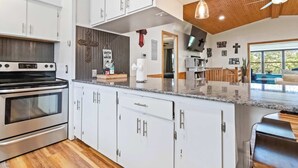 A modern kitchen with white cabinets, a stainless steel oven, and a granite countertop. - War Eagle Getaway (Springdale)