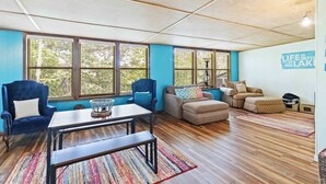 A spacious living room with a large window, a blue armchair, a sofa, and a coffee table. - War Eagle Getaway (Springdale)