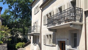 Un bâtiment à deux étages doté d’une façade en pierre, d’une porte en bois et d’un balcon orné de balustrades en fer forgé.