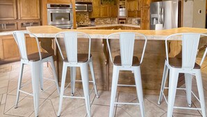 Een keuken met houten kastjes, roestvrijstalen apparatuur en een centraal eiland met barstoelen.