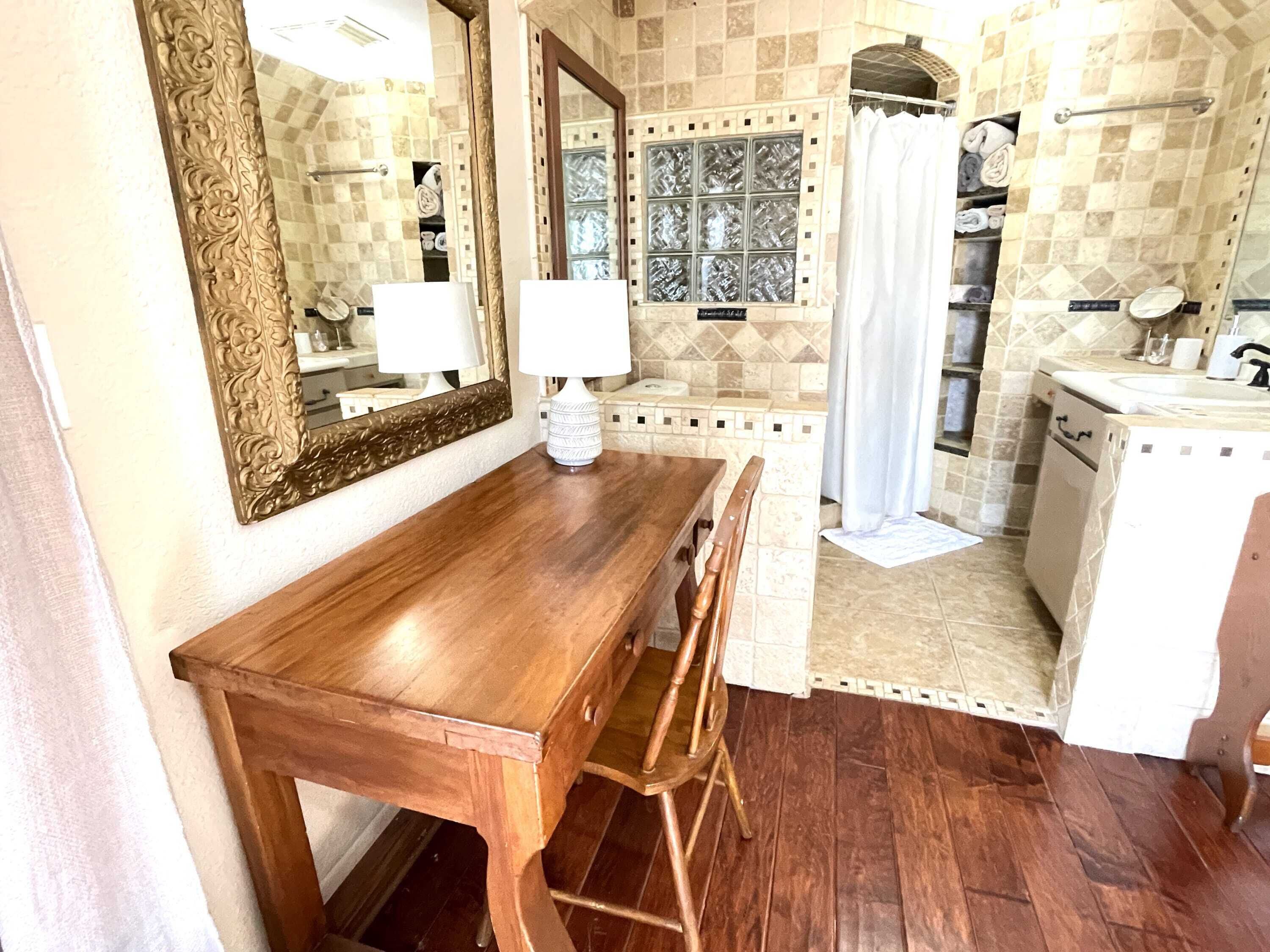 A bathroom with a wooden vanity, two mirrors, a shower with a glass door, and a tiled backsplash.