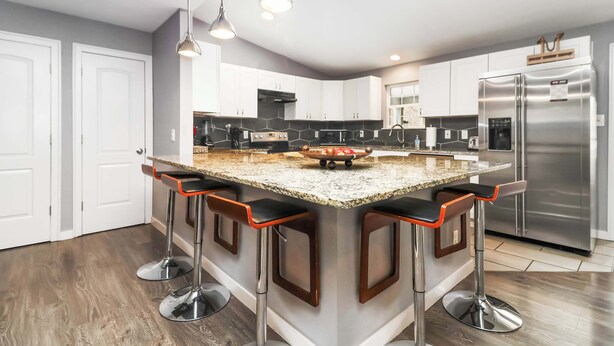 Una cocina moderna con una isla central, electrodomésticos de acero inoxidable y taburetes de bar.