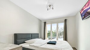 A bedroom with a bed, a bedside table, a window with curtains, and a ceiling light.