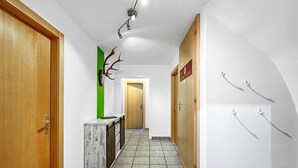 A hallway with wooden doors, a reception desk, a green accent wall, a deer antler decoration, and a sign for 'MOUNTAIN EXPRESS.'