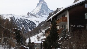 Eine Berghütte namens 'HAUS ASTRAL' mit Blick auf einen mit Schnee bedeckten Berggipfel.