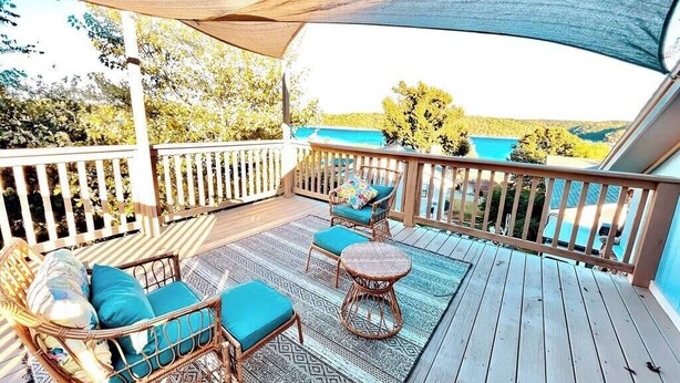 Una terraza cubierta al aire libre con mobiliario de mimbre y vista a un lago.