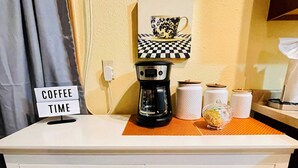 Una estación de café con cartel, cafetera, toallas de papel y frascos.