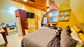 Un dormitorio con cama, escritorio y kitchenette.